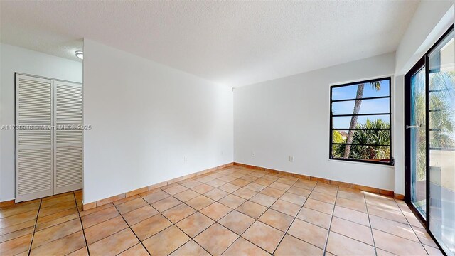 unfurnished room with light tile patterned floors and a textured ceiling