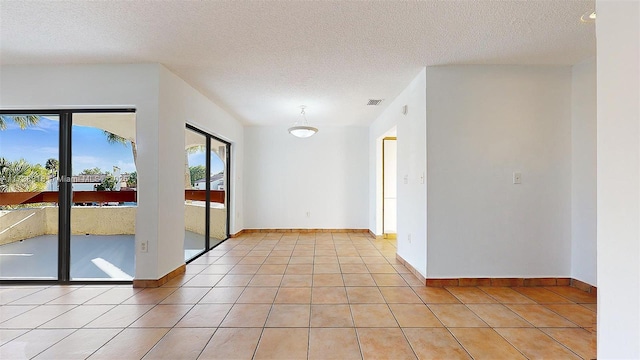 tiled empty room featuring a textured ceiling