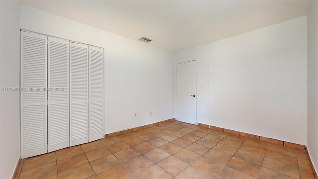 unfurnished bedroom with light tile patterned flooring and a closet