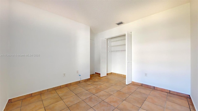 unfurnished bedroom with light tile patterned floors, a closet, and a textured ceiling