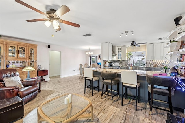 kitchen with white cabinetry, light stone counters, decorative backsplash, and wall chimney exhaust hood