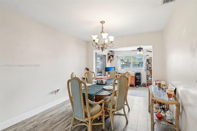 dining room with ceiling fan with notable chandelier and light wood-type flooring