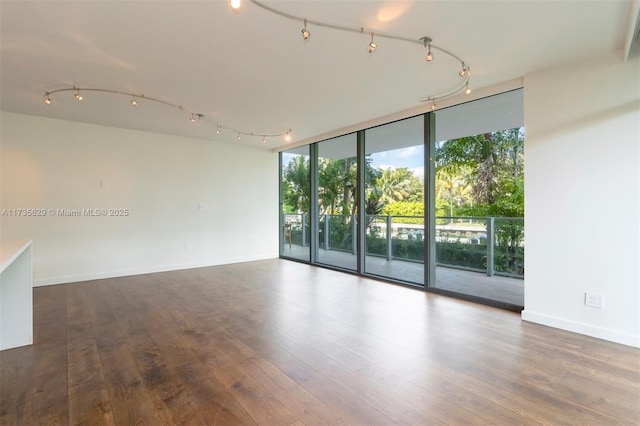 spare room featuring floor to ceiling windows, rail lighting, and wood-type flooring