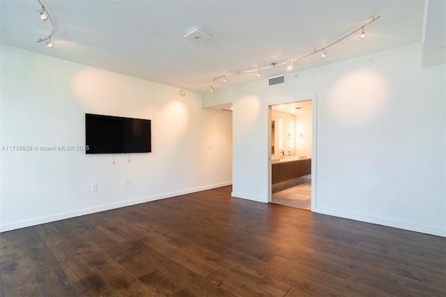 empty room with track lighting and dark hardwood / wood-style flooring