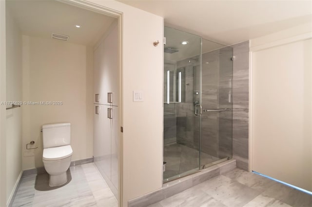 bathroom featuring a shower with shower door and toilet