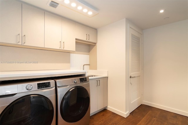 laundry room featuring cabinets, sink, dark hardwood / wood-style flooring, and washing machine and dryer