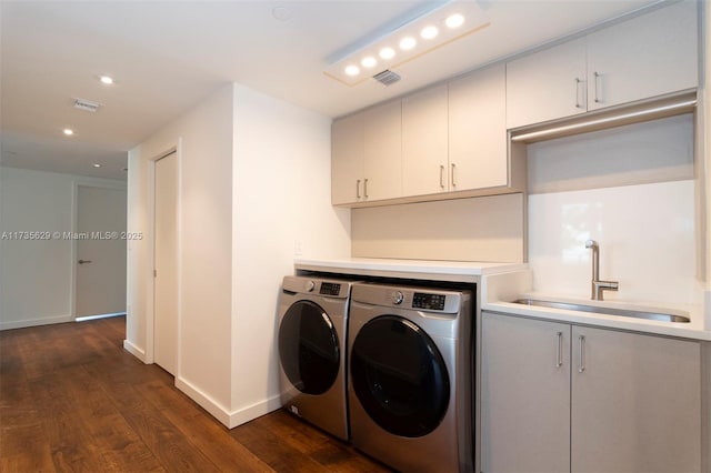 clothes washing area featuring cabinets, separate washer and dryer, sink, and dark hardwood / wood-style flooring