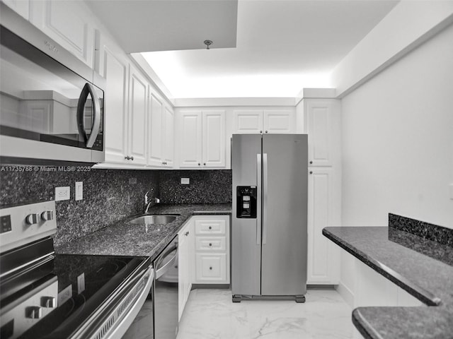 kitchen with sink, tasteful backsplash, dark stone countertops, stainless steel appliances, and white cabinets