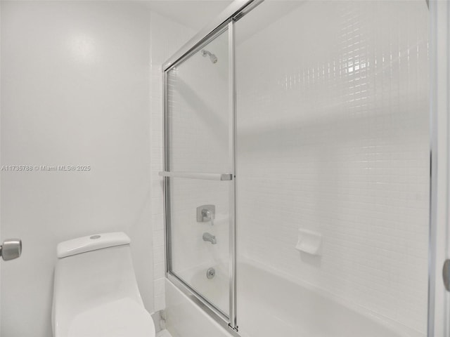 bathroom featuring bath / shower combo with glass door and toilet