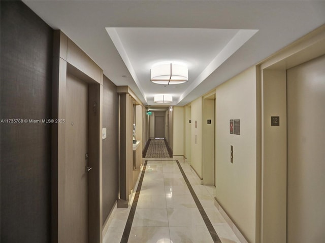 hallway with a raised ceiling and elevator