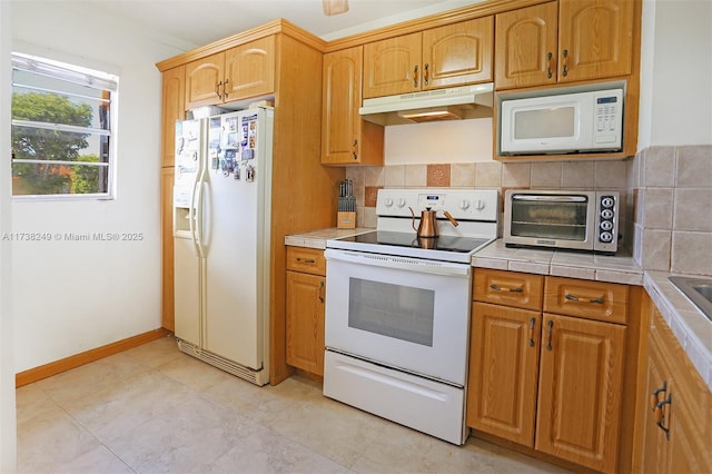 kitchen featuring white appliances, tile counters, and decorative backsplash