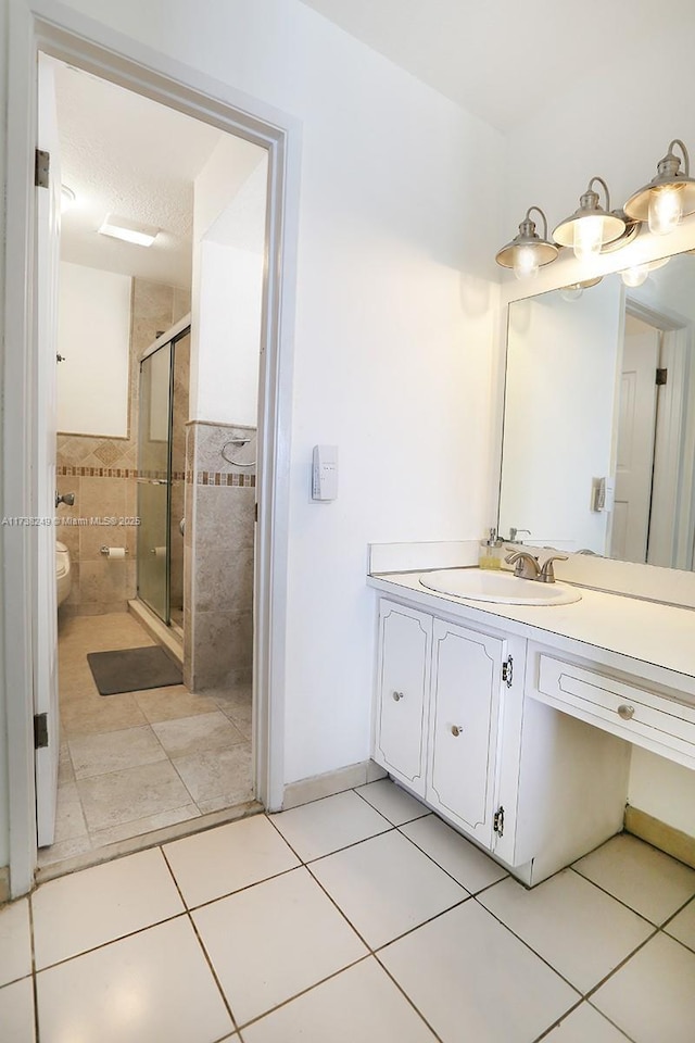 bathroom featuring walk in shower, vanity, and tile patterned flooring