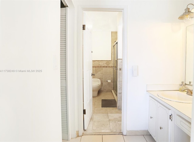 bathroom featuring walk in shower, tile patterned floors, toilet, tile walls, and vanity