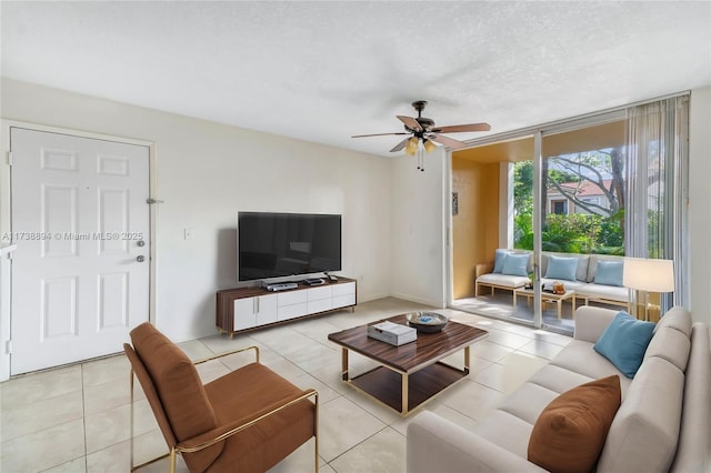 living room featuring ceiling fan, light tile patterned floors, and a textured ceiling