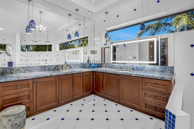 kitchen with hanging light fixtures, light stone countertops, sink, and an inviting chandelier