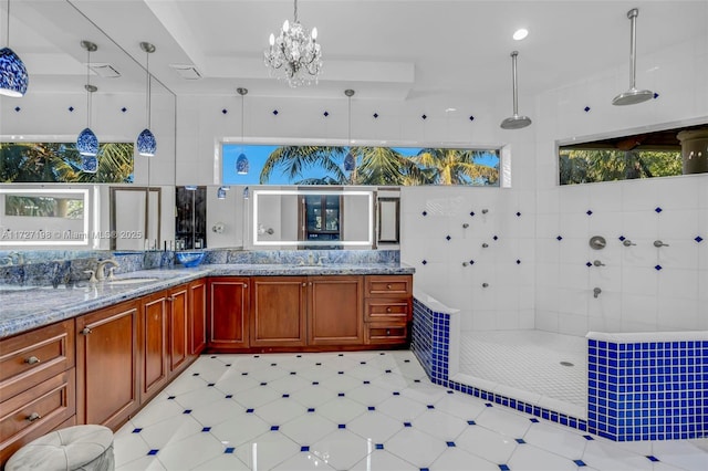 kitchen with light stone counters, a sink, a notable chandelier, and decorative light fixtures