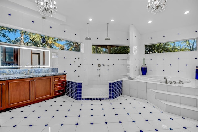 full bathroom featuring vanity, a garden tub, a notable chandelier, and walk in shower