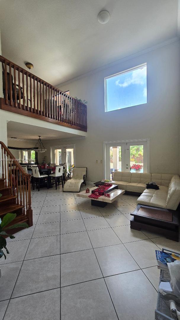 tiled living room featuring ornamental molding and a towering ceiling