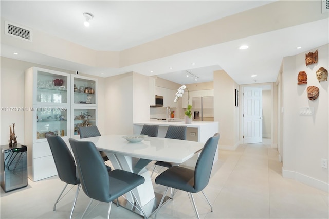 tiled dining space featuring wine cooler, sink, and rail lighting