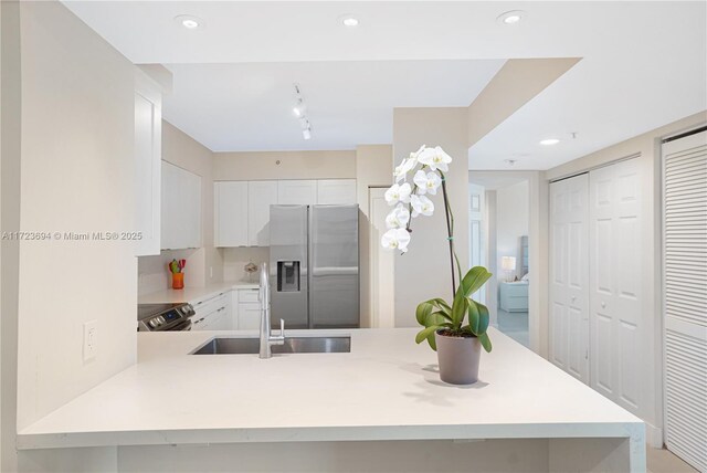 1155 Brickell Bay Dr Unit 704, Miami, FL 33131 - kitchen with stainless steel appliances, a sink, light countertops, white cabinets, and a peninsula