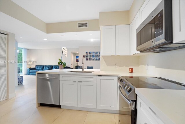 kitchen featuring stainless steel appliances, white cabinetry, sink, and light tile patterned flooring