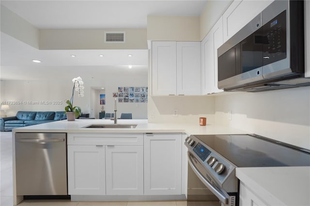 kitchen featuring white cabinetry, stainless steel appliances, kitchen peninsula, and sink