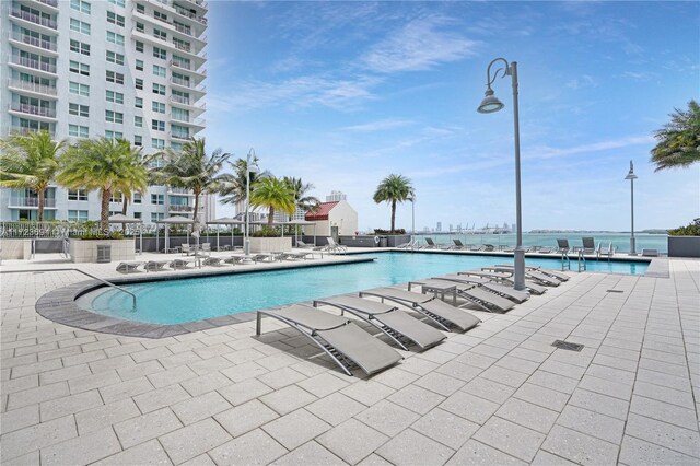 view of pool with a water view and a patio area