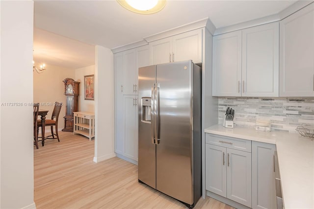 kitchen with white cabinets, decorative backsplash, light wood-type flooring, and stainless steel fridge with ice dispenser