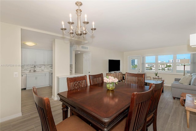 dining space featuring sink, a notable chandelier, and light wood-type flooring