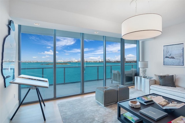 living room featuring a water view, expansive windows, and hardwood / wood-style floors