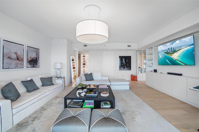 living room featuring built in shelves and light hardwood / wood-style flooring