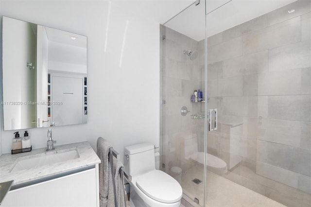 bathroom featuring vanity, a shower with door, and toilet