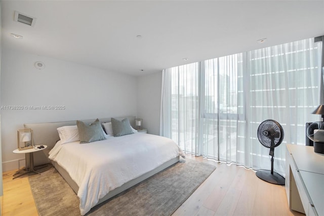 bedroom with floor to ceiling windows and light wood-type flooring