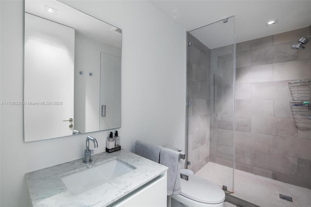 bathroom featuring vanity, a shower with shower door, and toilet