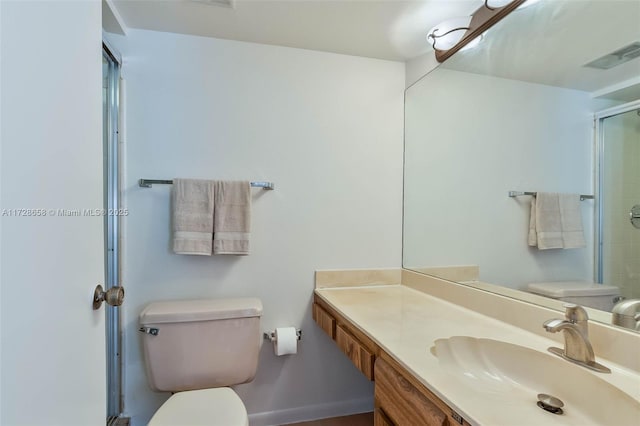 bathroom featuring vanity, toilet, and a shower with shower door