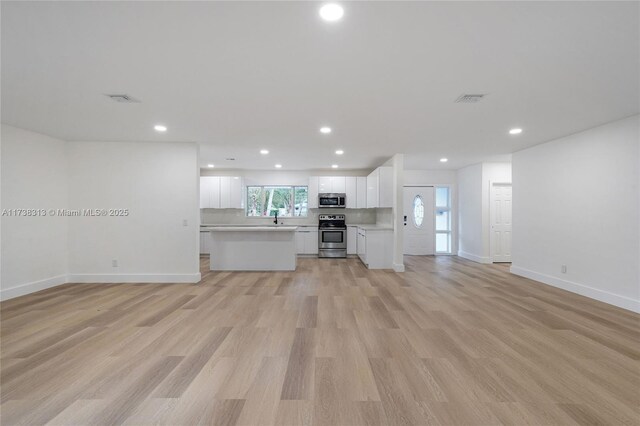 unfurnished living room with sink and light wood-type flooring