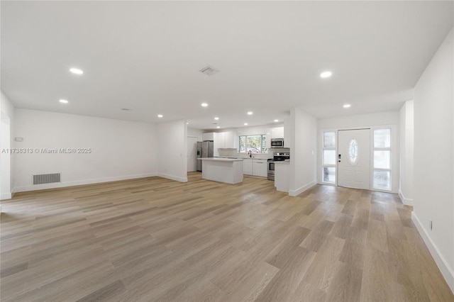 unfurnished living room with sink and light hardwood / wood-style floors