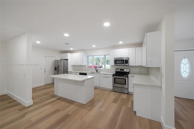 kitchen featuring tasteful backsplash, white cabinetry, sink, light hardwood / wood-style floors, and stainless steel appliances