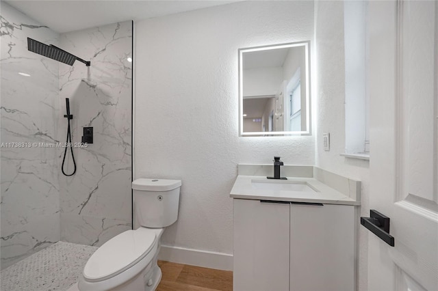 bathroom with vanity, hardwood / wood-style flooring, toilet, and a tile shower