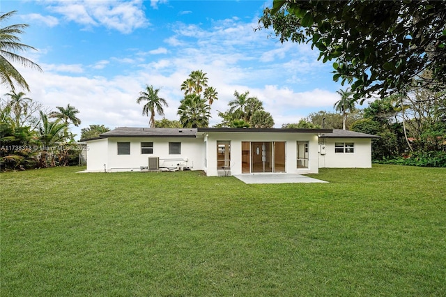 back of property with central AC unit, a patio area, and a lawn