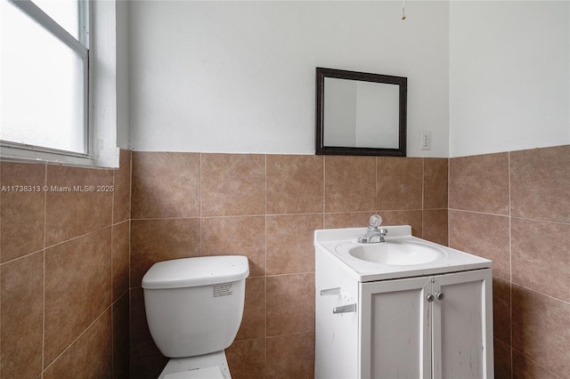 bathroom with vanity, tile walls, toilet, and a healthy amount of sunlight