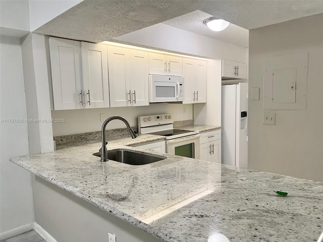 kitchen featuring white appliances, white cabinetry, a sink, and light stone countertops