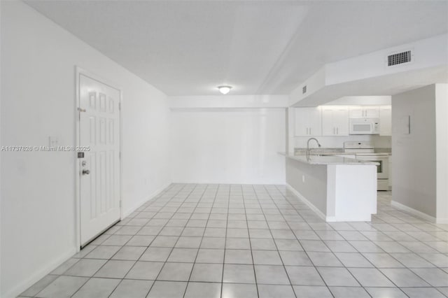 spare room with light tile patterned floors, baseboards, visible vents, and a sink