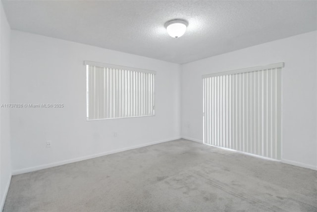 spare room featuring baseboards, a textured ceiling, and carpet flooring