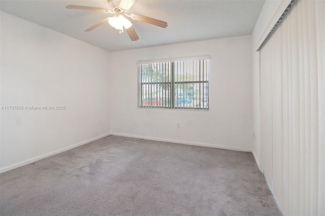 unfurnished room featuring carpet flooring, ceiling fan, a textured ceiling, and baseboards