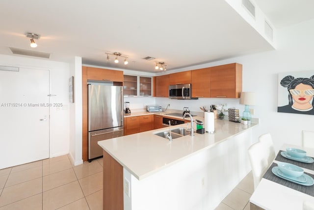 kitchen featuring light tile patterned flooring, stainless steel appliances, kitchen peninsula, and sink