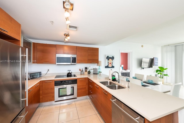 kitchen with rail lighting, sink, light tile patterned floors, kitchen peninsula, and stainless steel appliances