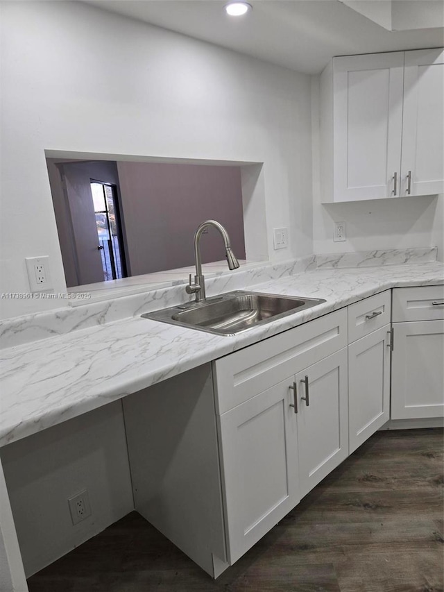 kitchen featuring sink, white cabinetry, light stone counters, dark hardwood / wood-style floors, and kitchen peninsula