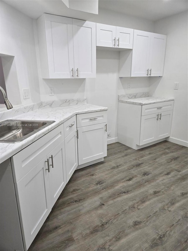 kitchen featuring dark hardwood / wood-style flooring, sink, light stone countertops, and white cabinets