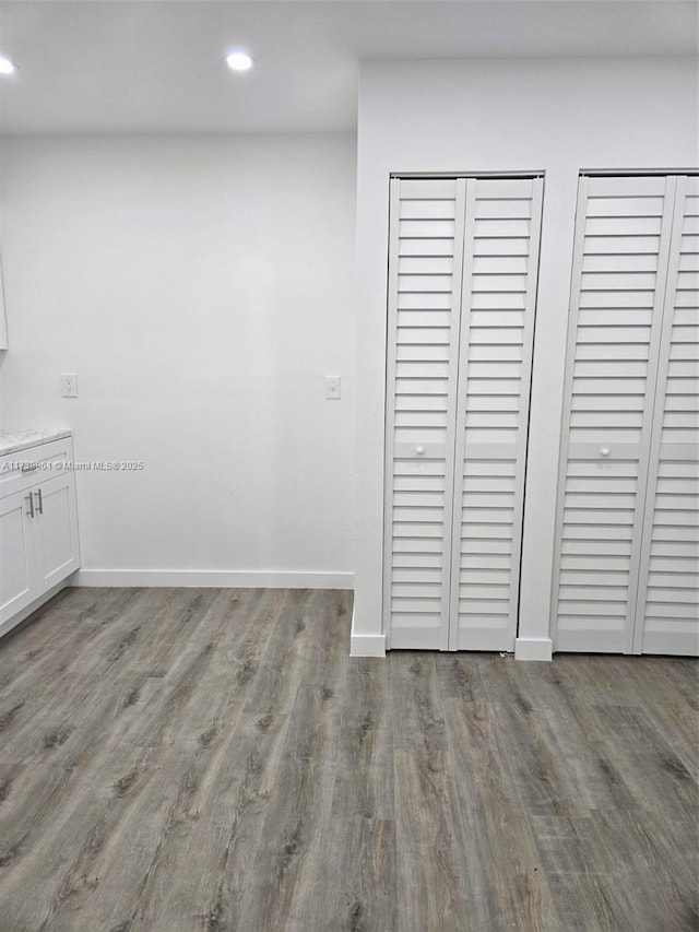 unfurnished bedroom featuring hardwood / wood-style floors and two closets